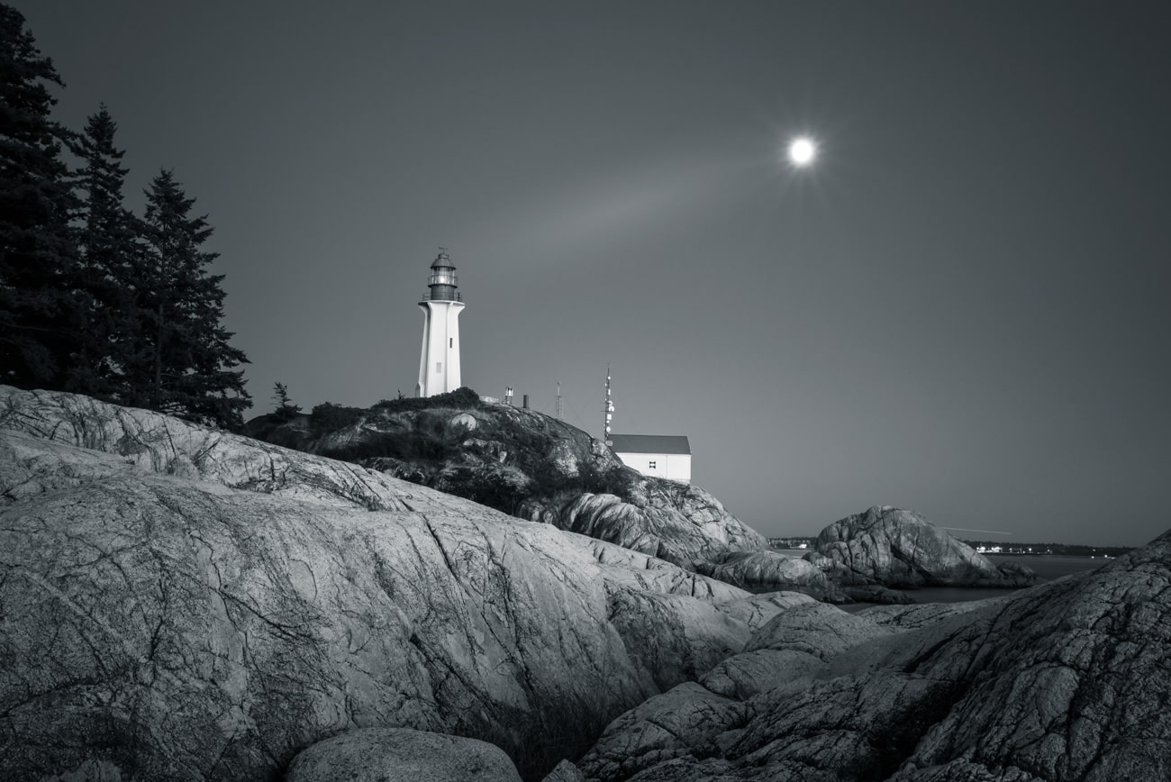 Lighthouse in Black and White in West Vancouver, Canada with rising moon landscape.