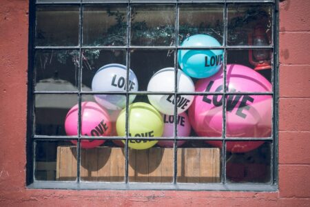 Colorful Love balloons behind a window with iron bars.