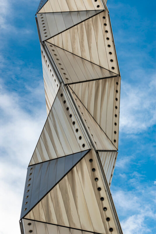 Art Tower Mito, close-up of its spiral, triangular titanium panels against a bright blue sky in Mito, Ibaraki, Japan.