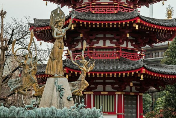 Bronze Prayer and Peace statue before Kawasaki Daishi's octagonal pagoda and Yakushi Hall in Kawasaki, Japan.