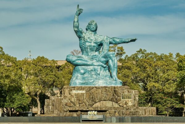 Nagasaki Peace Statue in Nagasaki Peace Park, Japan, with trees and cloudy sky in the background.